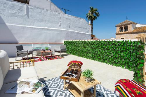 a patio with chairs and a green hedge at Sunstay Arroyo House Velez in Vélez-Málaga