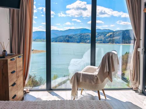 a bedroom with a view of a large window at Moon Lake Bicaz - Casa Oia in Buhalniţa