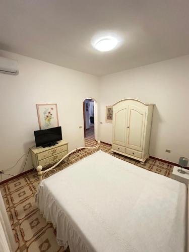 a bedroom with a large white bed and a television at Da mare in Ginosa Marina