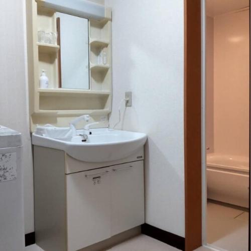 a bathroom with a sink and a mirror and a tub at Lemon みやざき in Miyazaki