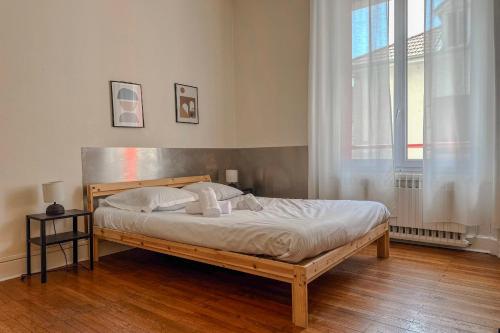 a bedroom with a wooden bed with white sheets and a window at #EU L'Authentique in Grenoble