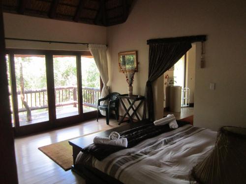 a bedroom with a bed and a balcony at Mingwe Private Game Lodge in Mabula