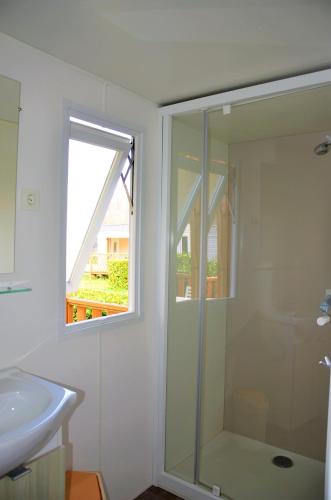 a bathroom with a shower and a sink and a window at Flower Camping Les Mijeannes in Rieux-de-Pelleport