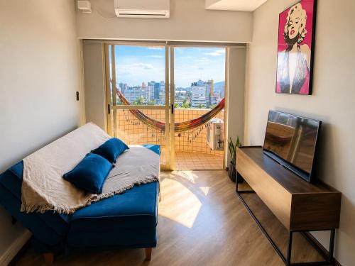 a bedroom with a bed and a television and a balcony at Apê completo bem no centro in Joinville