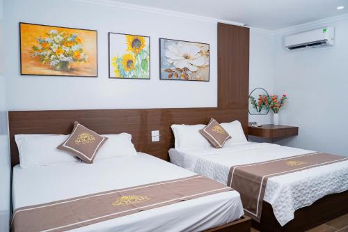 two beds in a hotel room with paintings on the wall at Khách sạn SOLAR HOTEL in Phúc Trì