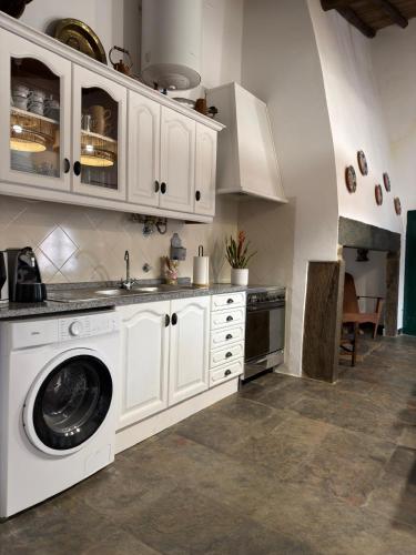 a kitchen with white cabinets and a washing machine at Casa Velha in Mourão