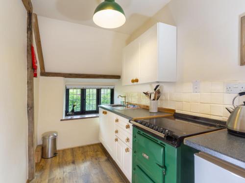 a kitchen with white cabinets and green appliances at Apartment The Appleloft suite by Interhome in Holsworthy