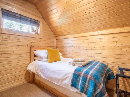 a bedroom with a bed in a wooden cabin at Chalet Beekeepers Bothy by Interhome in Coldstone