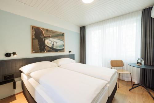 a bedroom with a large white bed and a table at Fred Hotel Central in Zurich