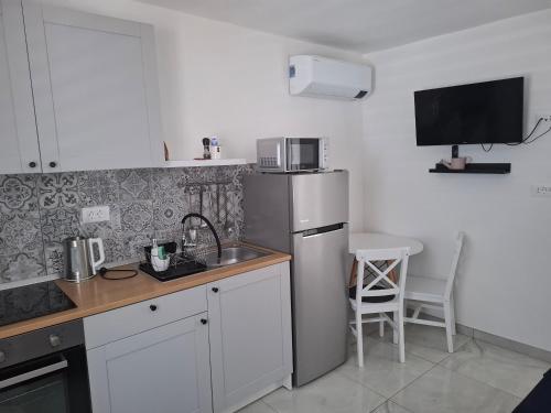 a kitchen with a refrigerator and a table with a chair at Apartmani T'n'T in Pag