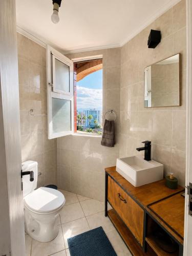 a bathroom with a toilet and a sink and a window at Apê completo bem no centro in Joinville