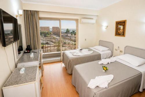 a hotel room with two beds and a balcony at Emilio Hotel in Luxor