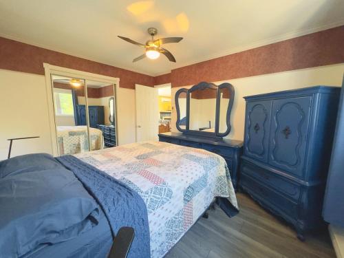a bedroom with a blue bed with a dresser and a mirror at Chalet au bord du lac à la Baie Boudreault in Alma