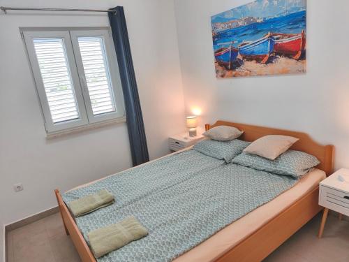 a bedroom with a bed and a painting on the wall at Slanraj apartman in Jadrtovac