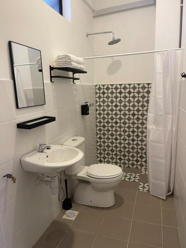 a white bathroom with a toilet and a sink at Studio Inap Seri Iskandar in Kampong Bota Road