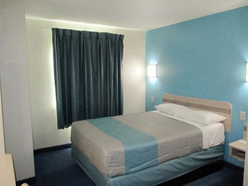 Schlafzimmer mit einem Bett mit blauen Wänden und einem Fenster in der Unterkunft Motel 6-Kingdom City, MO in Kingdom City