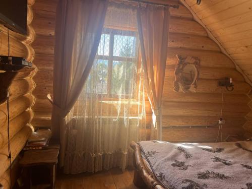 a bedroom with a window in a log cabin at Думанія in Verkhovyna