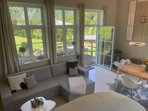 a living room with a couch and a table and windows at Chalet Alpenlicht in Oberstdorf