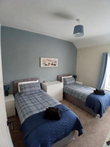 two beds in a bedroom with blue walls at Hilltop Retreat at Banktop in Southowram