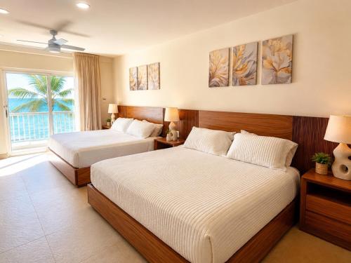 a hotel room with two beds and a window at Luxury Beachfront Condo at Krystal Grand Resort - NEWLY REMODELED & NEWLY FURNISHED in Bucerías
