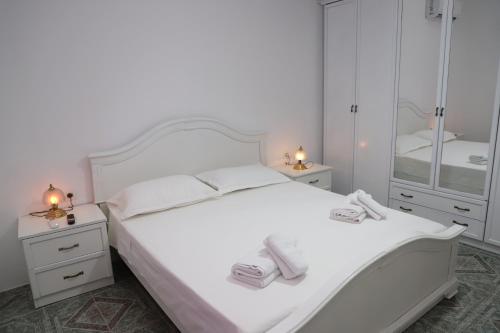 a white bedroom with a white bed and two night stands at A&B Berat in Berat