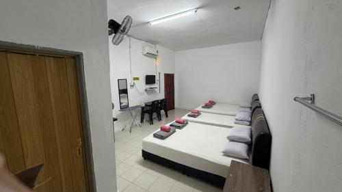 a room with three beds and a desk in it at Bunga Raya Guest House BALING in Baling