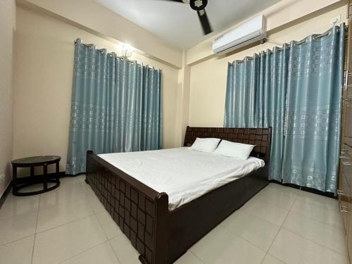 a bedroom with a bed with blue curtains at Vacation House a Service Apartment in Cox's Bazar