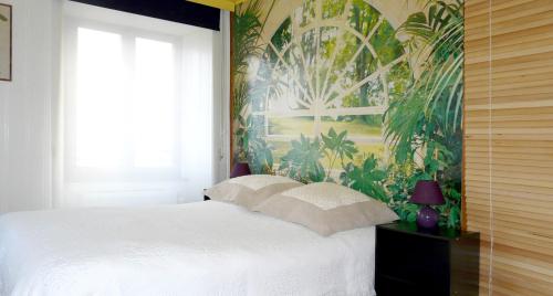 a bedroom with a white bed with a tropical wallpaper at Lina et Anaë in Saint-Nabor