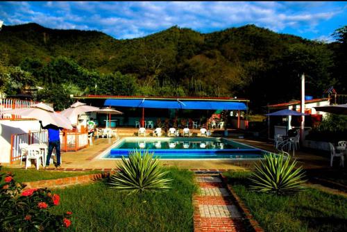 a person standing by a swimming pool with a house at La melosa in Girardot