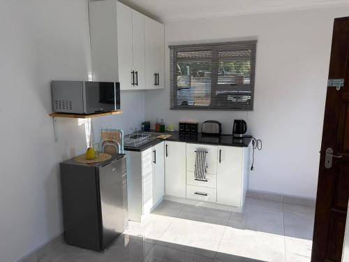 a kitchen with white cabinets and a microwave at 47 on Cleland in Pietermaritzburg