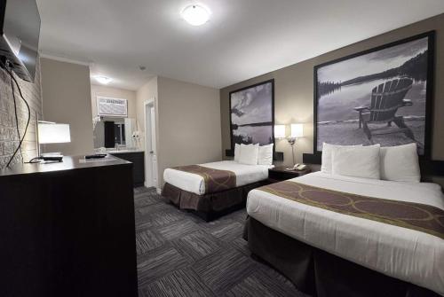 a hotel room with two beds and a desk at Super 8 by Wyndham Guelph in Guelph
