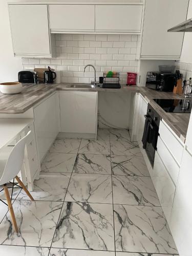 a kitchen with white cabinets and a marble floor at 2 bed- walkable train and beach apartment in Crosby