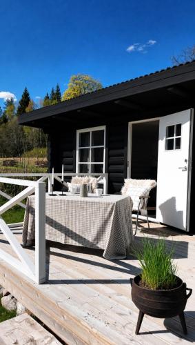 eine Holzterrasse mit einem Tisch und ein schwarzes Haus in der Unterkunft Vildstugan in Björksjön