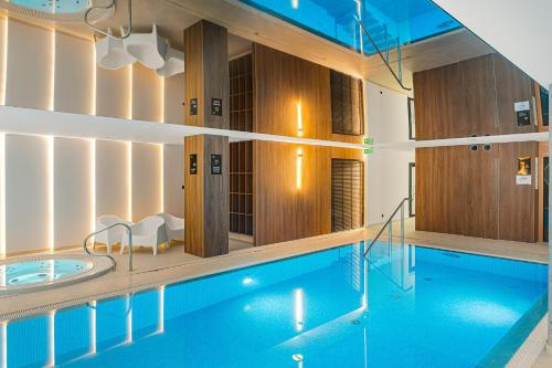 a swimming pool with a tub in a building at Cortaderia Haven - SPA - Basen, Jacuzzi, Sauna & Parking in Ustronie Morskie
