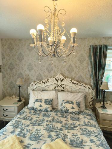 a bedroom with a blue and white bed with a chandelier at Waterloo Cottage in Barnard Castle