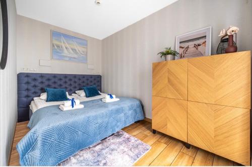 a bedroom with a blue bed and a wooden dresser at Mechelinki Enjoy in Mechelinki