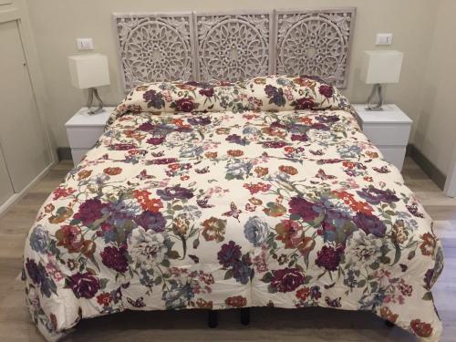 a bed with a floral bedspread on it with two lamps at Dimora Spina in centro in Campobasso