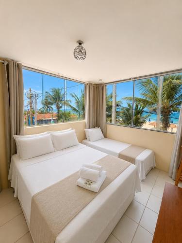 two beds in a room with a view of the ocean at Pousada Recanto Paradise in Porto De Galinhas
