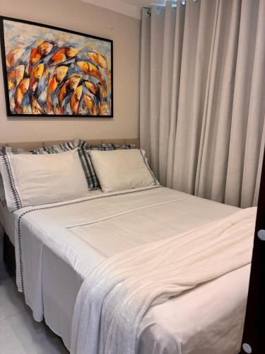 a bed in a bedroom with a painting on the wall at Quarto acolhedor in Aracaju