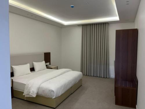 a bedroom with a large bed with white sheets at الغاف للشقق المخدومة in Sarat Abidah