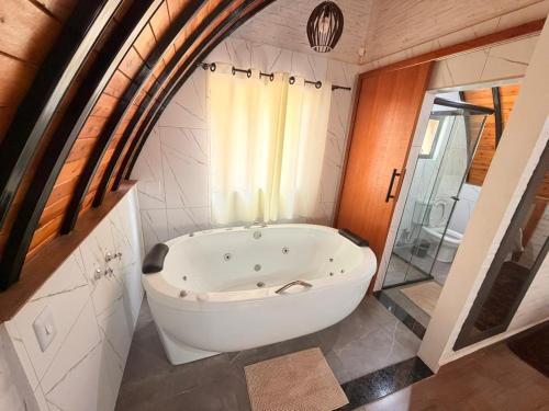 a large white bath tub in a bathroom at Recanto sol nascentre cabanas in Monte Verde