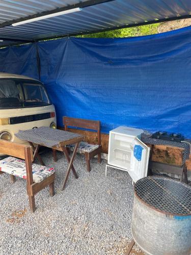 a blue tent with benches and a grill and a car at Kombi Home in Piedade