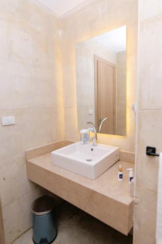 a bathroom with a white sink and a mirror at Settle inn Jebal apartments in Cairo