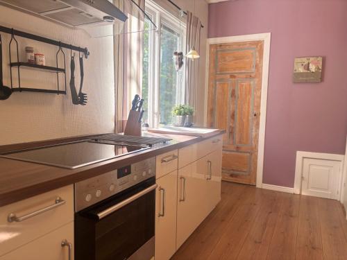 a kitchen with a stove and a sink and a window at Banvaktstuga anno 1905 in Fliseryd