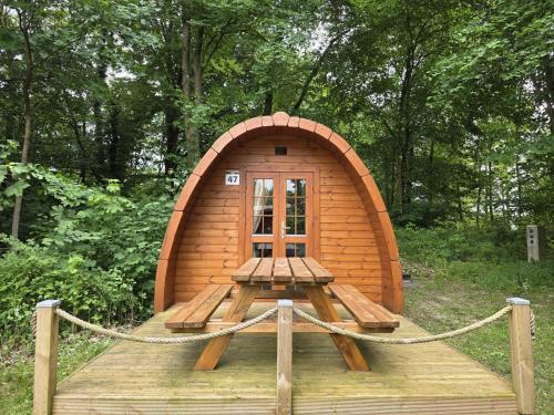 a small wooden cabin with a bench in the woods at 47 Camping Pod "Flut" in Silberstedt