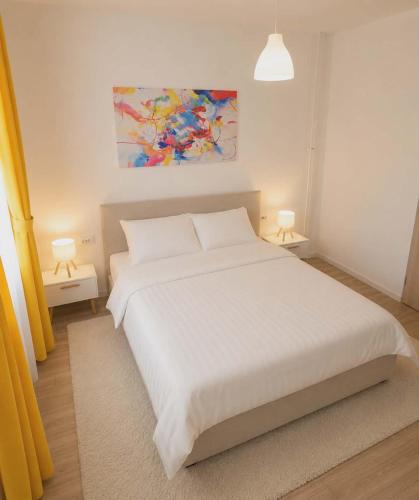 a white bed in a bedroom with two lamps at MM Central Apartment with Parking in Skopje