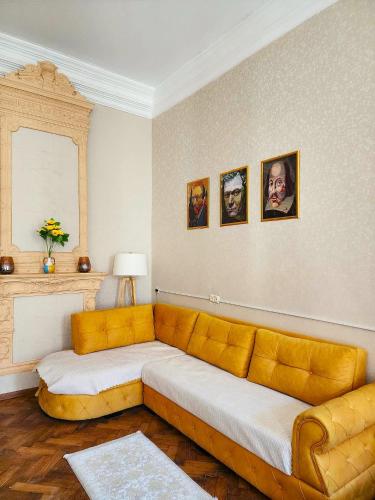 a living room with a yellow couch and pictures on the wall at Gallery inn in Kutaisi