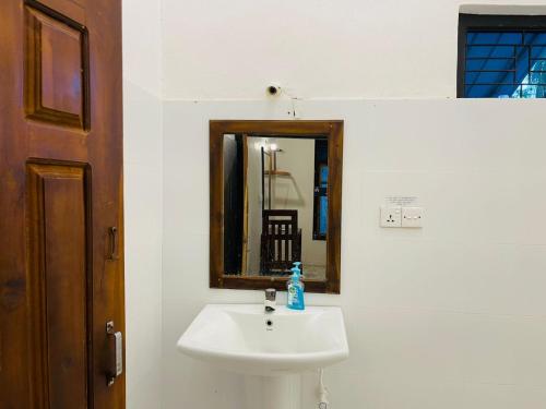 a bathroom with a white sink and a mirror at Lagoon Hostel in Arugam Bay