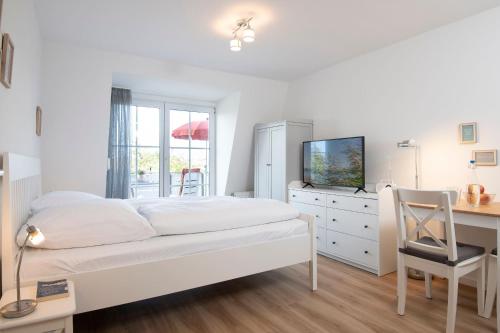 a bedroom with a white bed and a desk and a computer at Kleine Meerzeit in Dahme