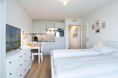 a white bedroom with a bed and a kitchen at Kleine Meerzeit in Dahme